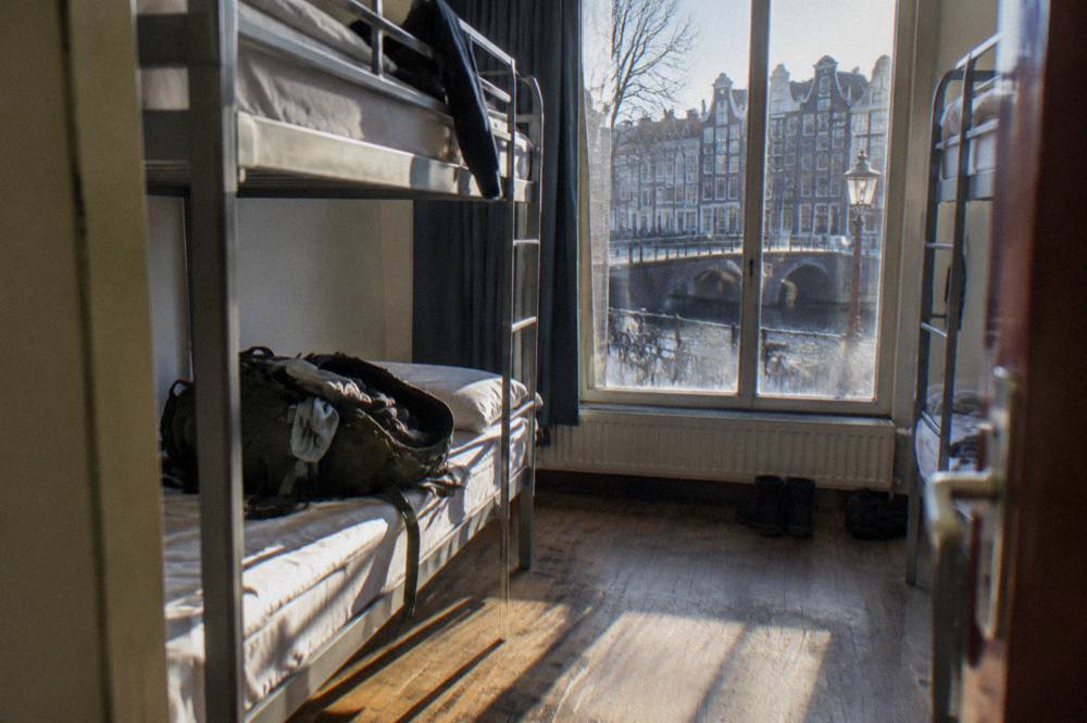 A row of bunk beds in a bright hostel dorm room with a window