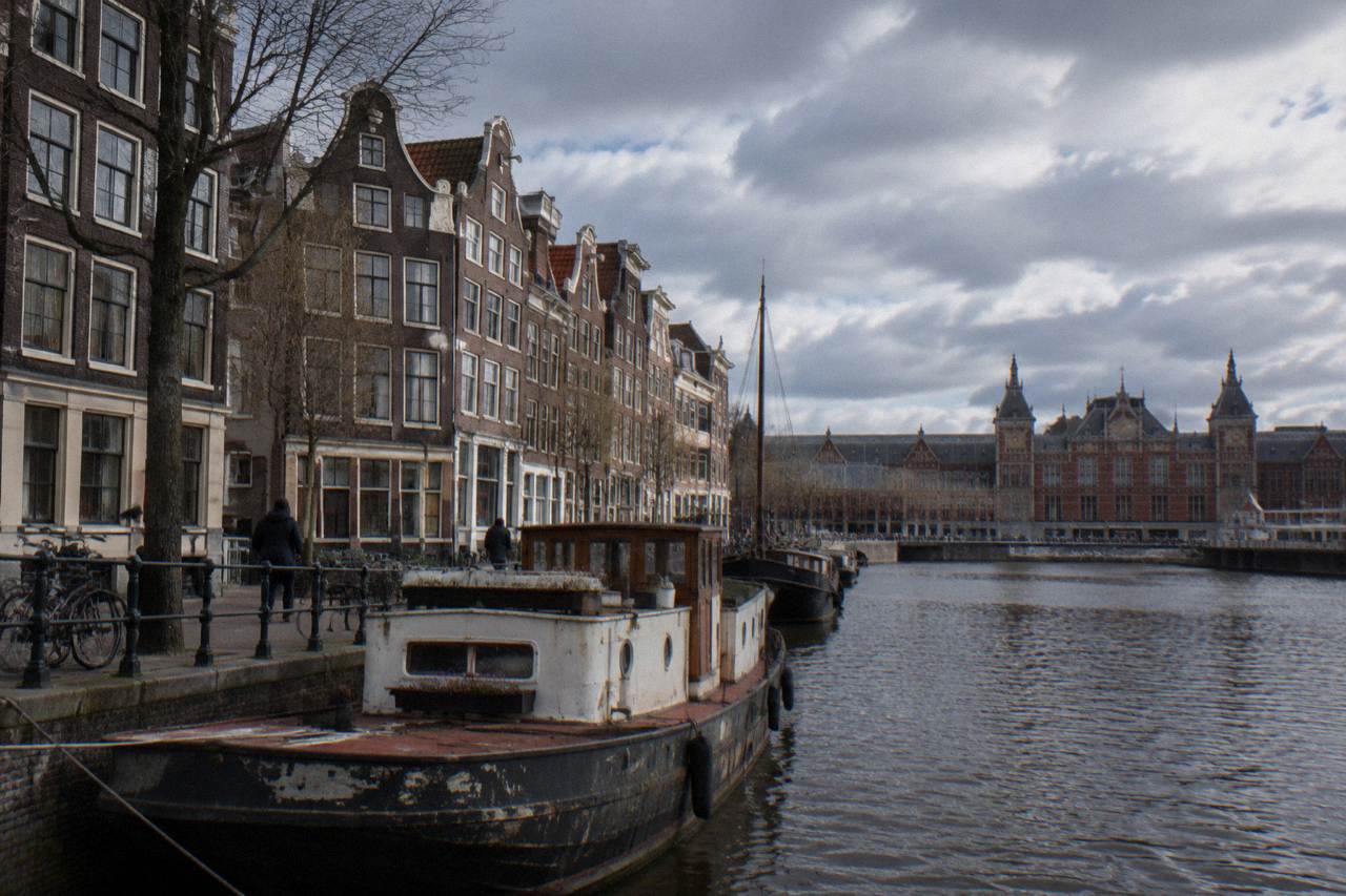 A quiet Amsterdam canal street with narrow brick buildings and bicycles parked along the water