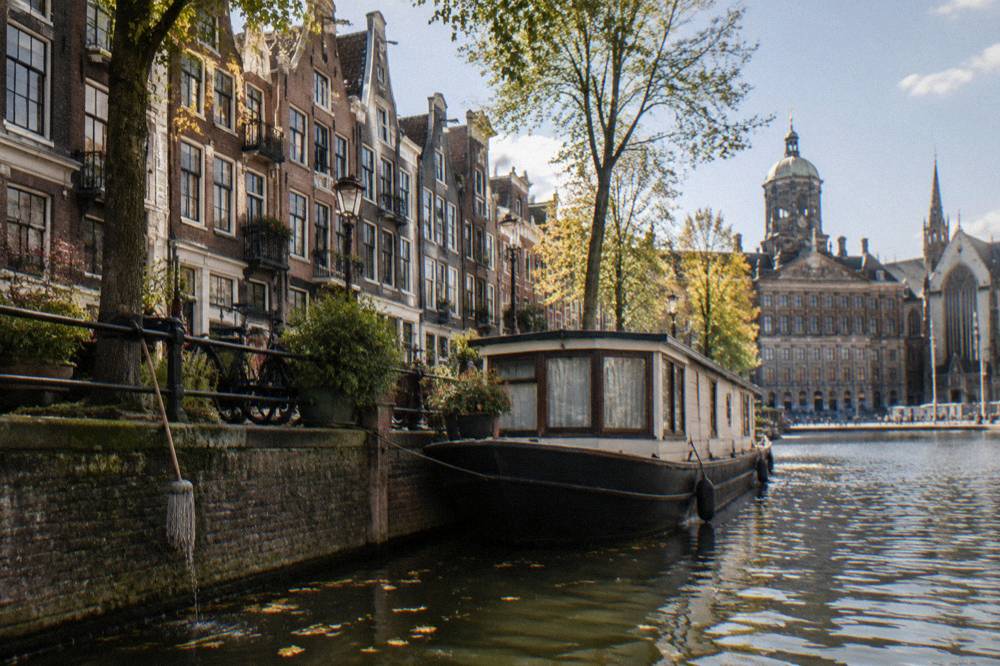 A narrow Amsterdam street with bicycles parked against railings beside a canal