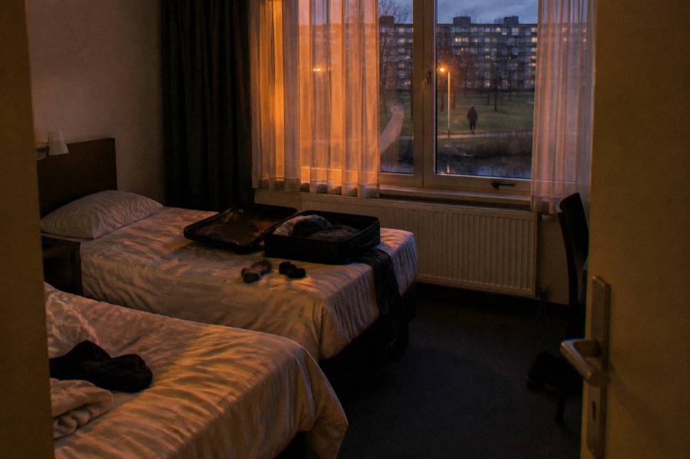 Budget hotel room interior with twin beds and a window over a street