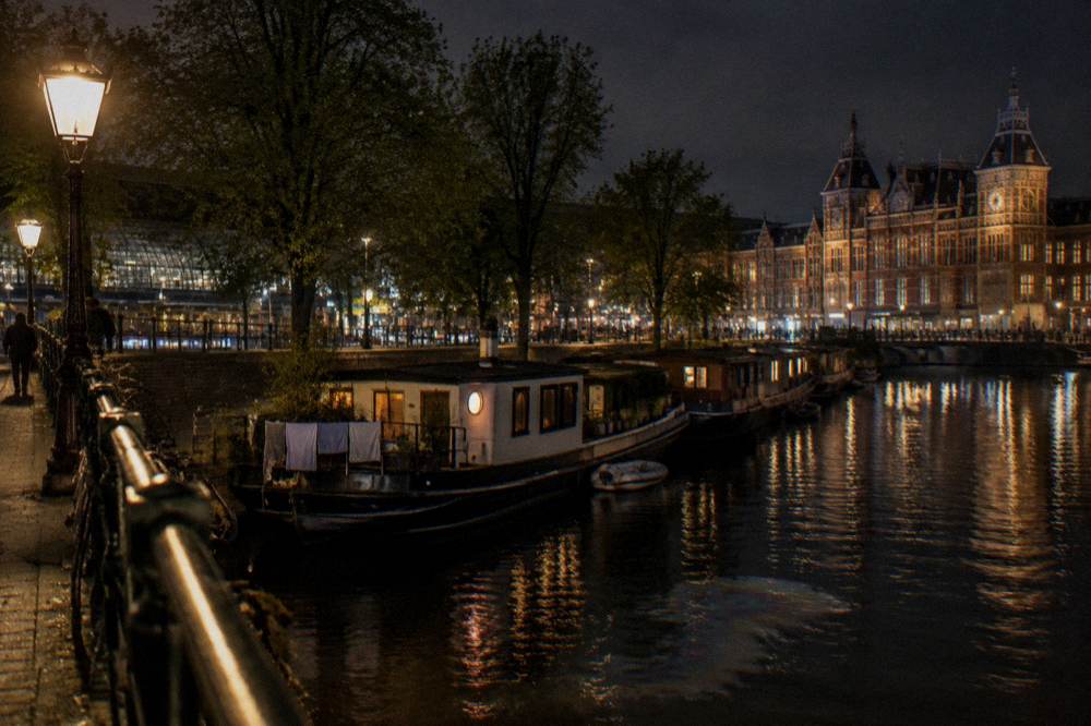 Evening view of a canal with lit bridge and moored houseboats