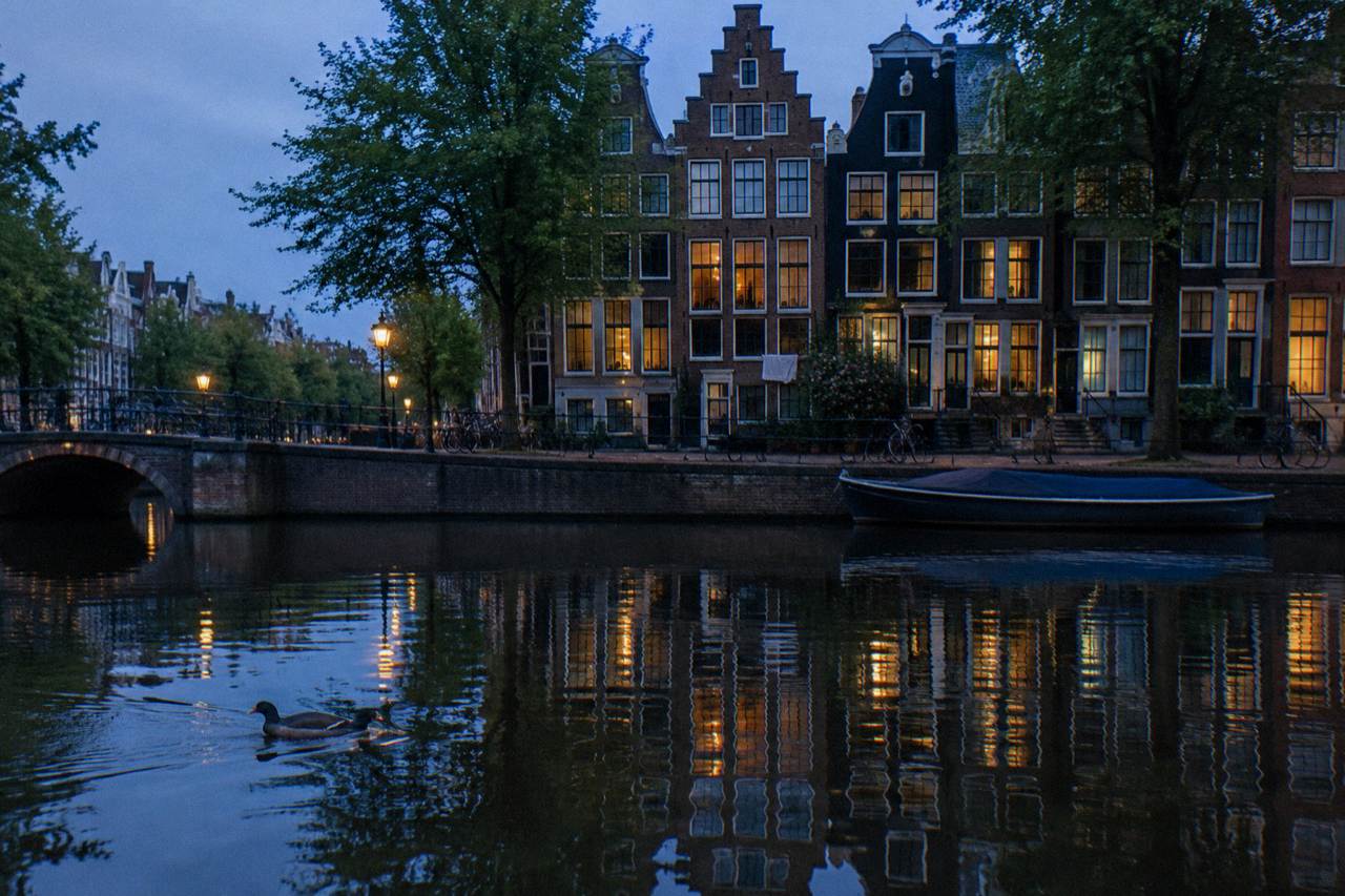 Canal-side hostel building at dusk with bicycles parked along the water