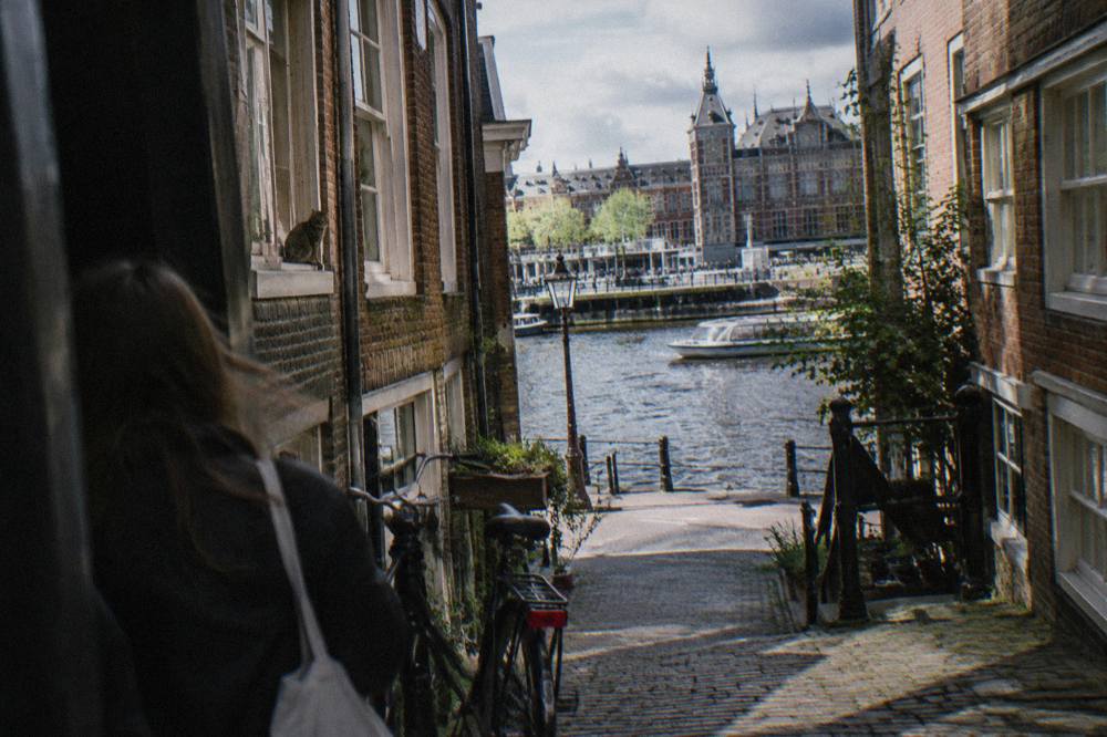 Narrow Amsterdam street with canal-side houses and bicycles