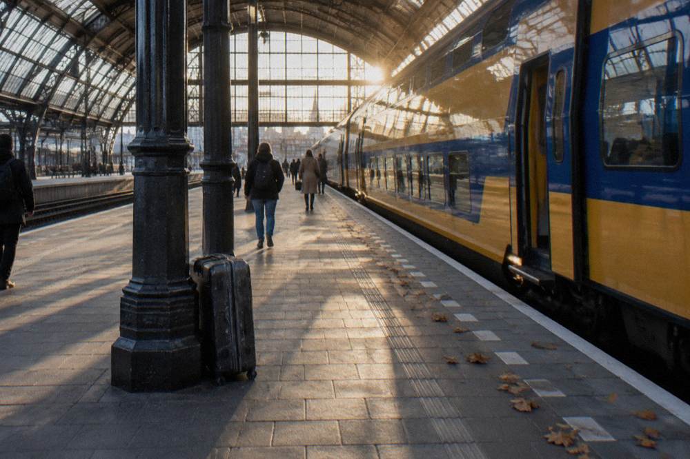 A train platform at an Amsterdam station with a stationary passenger train