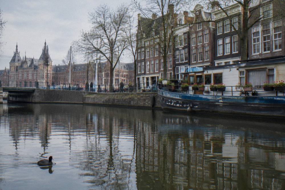 A row of tall narrow canal houses reflected in still water on an Amsterdam gracht