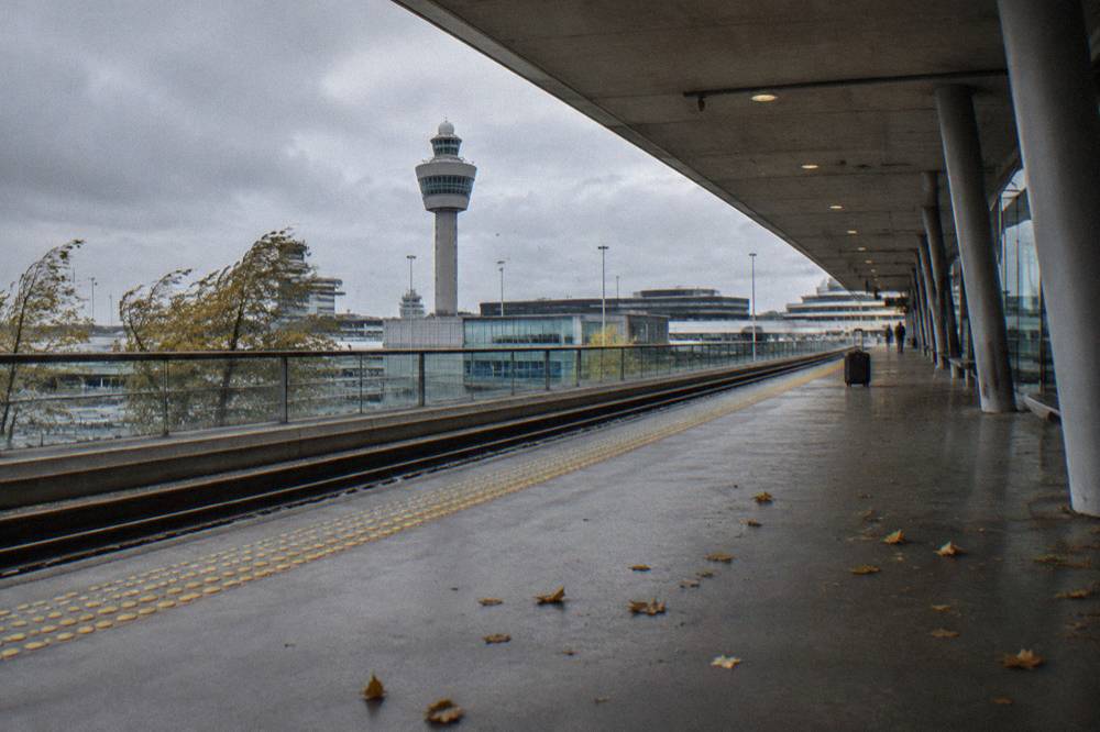 Train platform at an airport railway station with a yellow sign showing departures