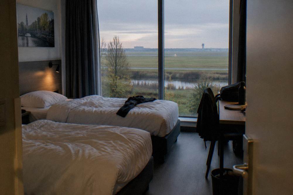 Hotel room with twin beds and a window facing a runway light in early morning