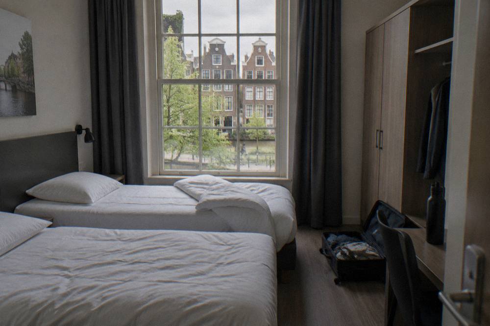 A tidy budget hotel room with two single beds and a window onto a quiet street