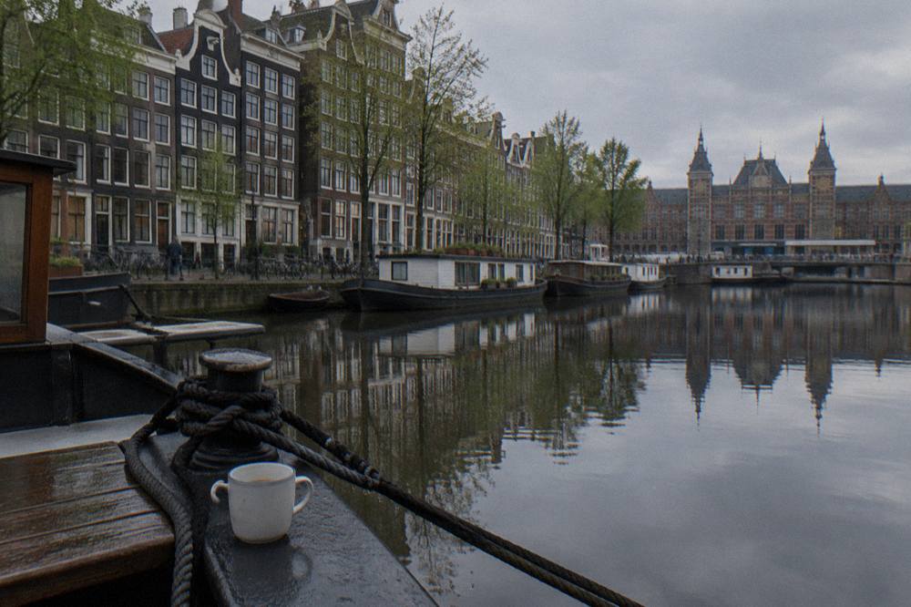 Row of canal houses reflected in still Amsterdam canal water on an overcast morning