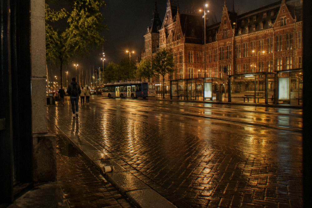 An empty city street at night lit by lamps near the central station area