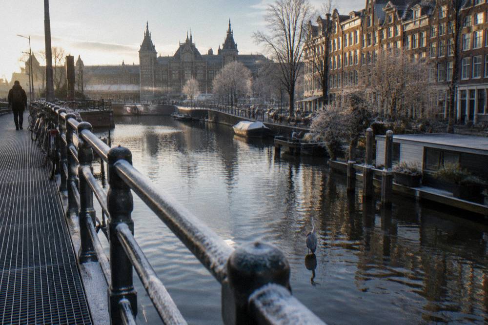 A bicycle bridge crossing an Amsterdam canal with apartment buildings behind