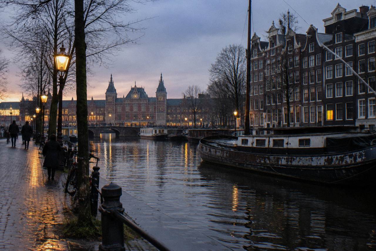 A quiet Amsterdam canal street with narrow brick buildings and parked bicycles at dusk