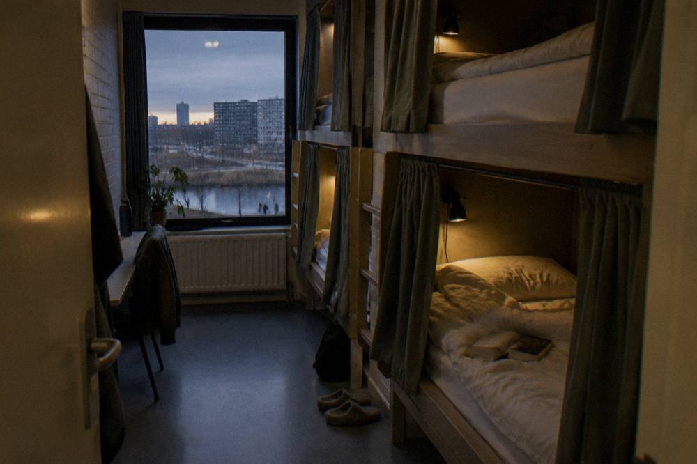 Bunk beds with curtains and personal lights in a calm hostel dorm room
