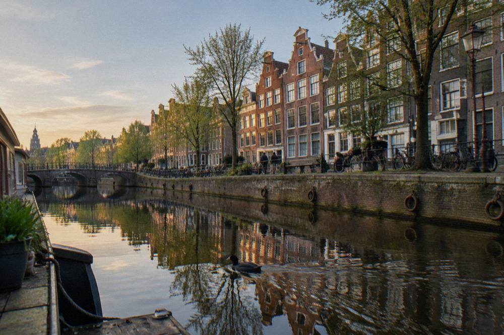 Amsterdam canal houses reflected in still water in early evening