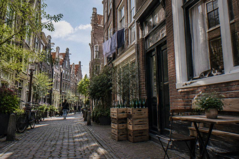 A narrow Amsterdam street with tall gabled houses above the pavement