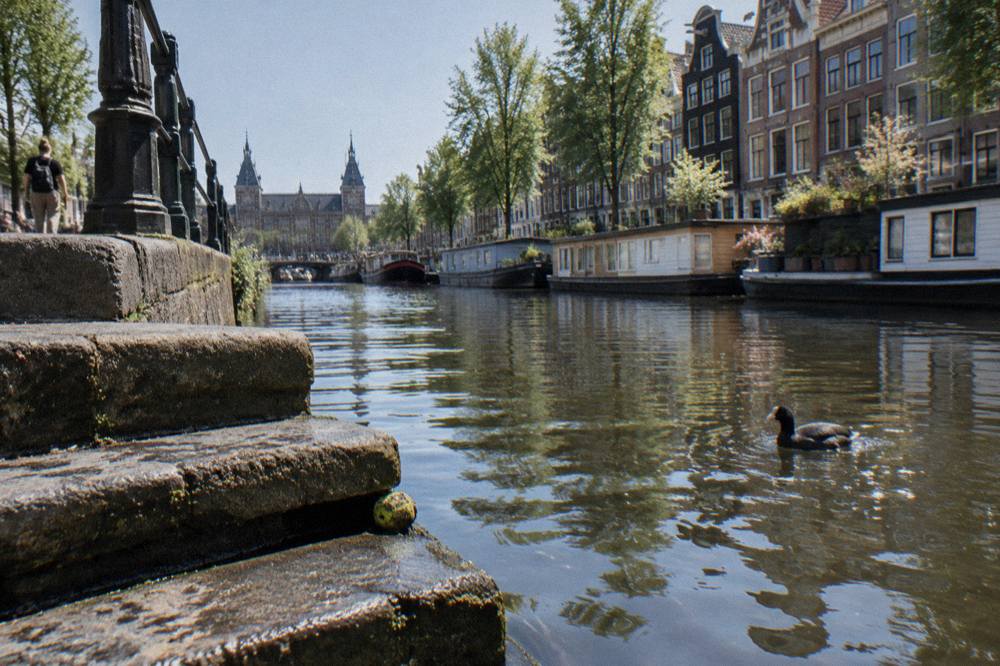 A quiet canal in central Amsterdam with narrow gabled houses reflected in the water
