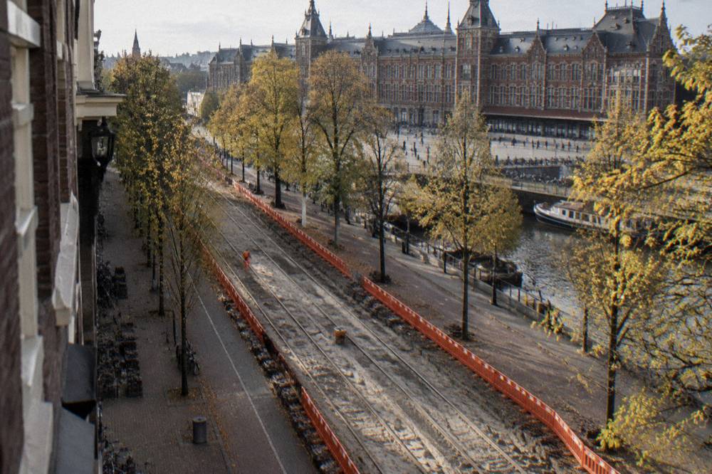 Amsterdam tram track under repair with orange barriers and diverted signage on a tree-lined street
