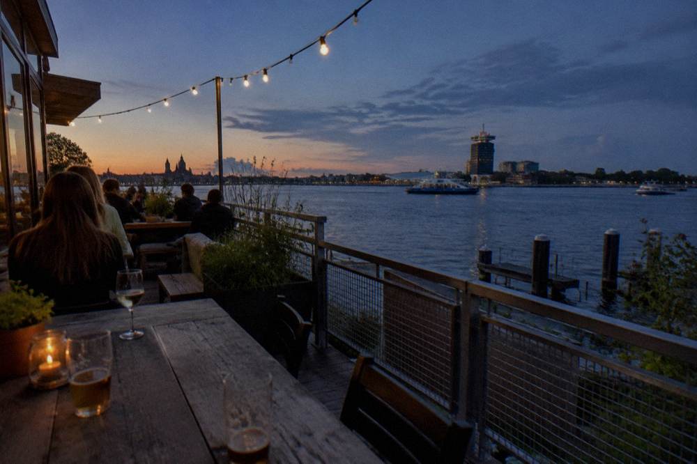 Evening view of a modern hostel terrace facing the water in Amsterdam Noord