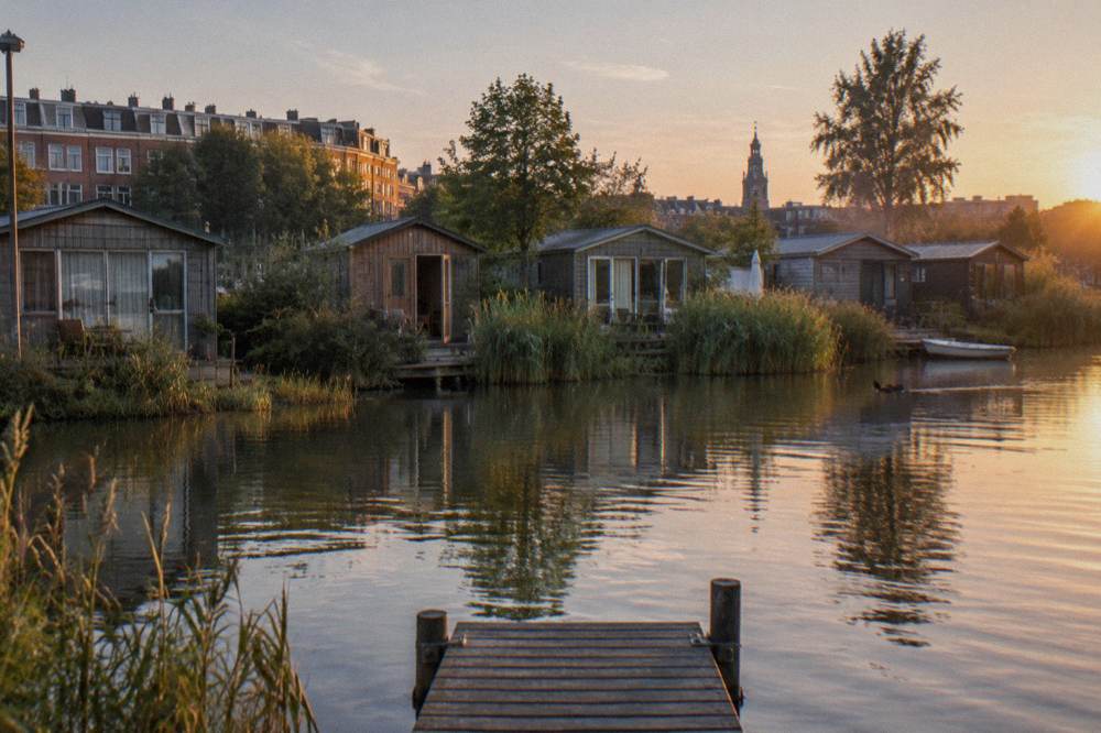 A row of small wooden cabins beside water at the edge of Amsterdam