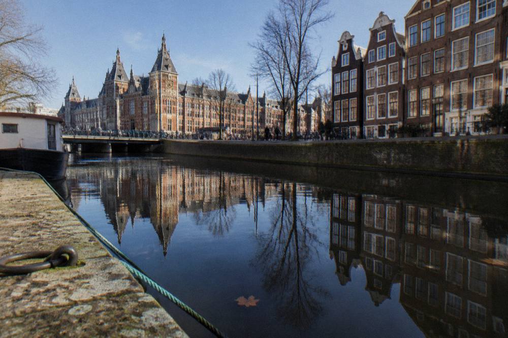 A row of Amsterdam canal houses reflected in still water
