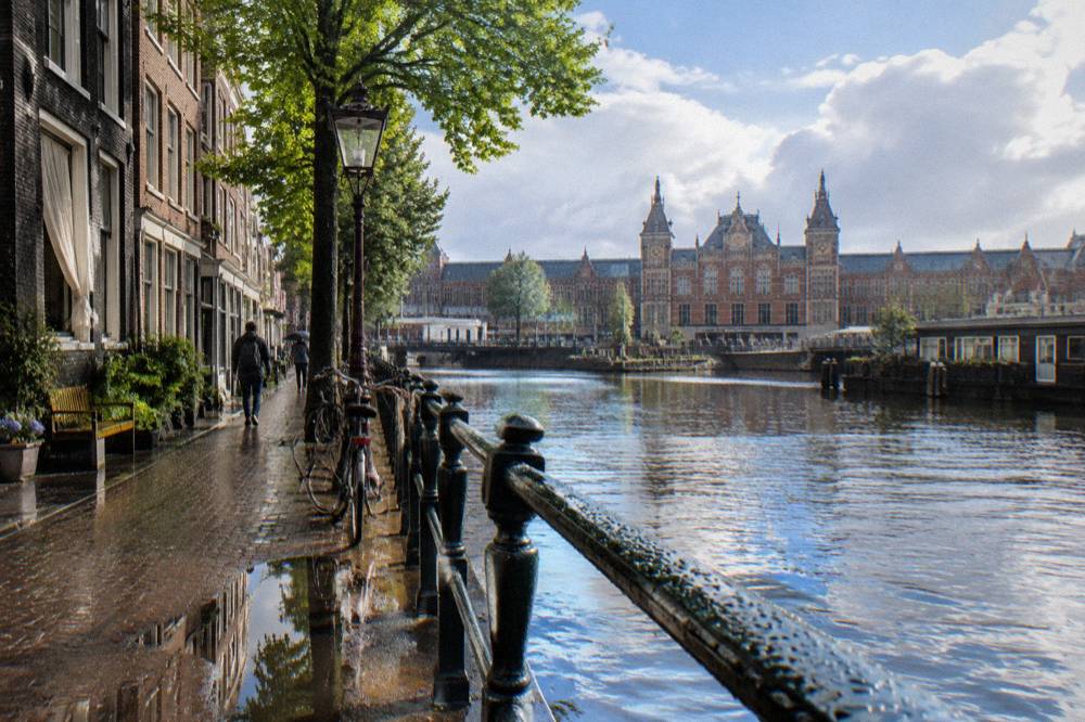 An Amsterdam street with bicycles parked along a canal railing