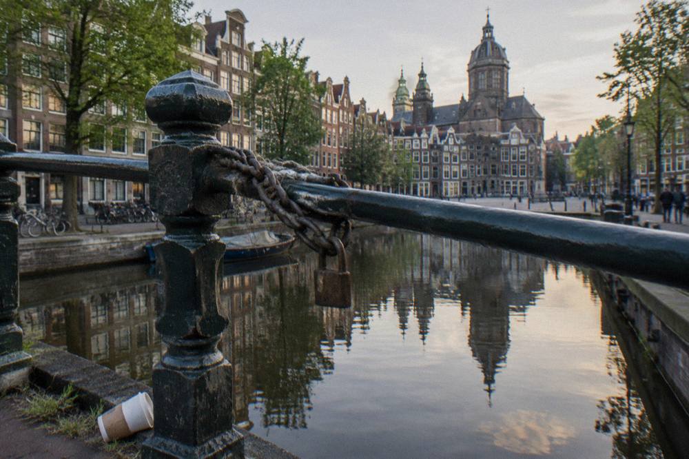 Amsterdam canal ring street with bicycles chained to a bridge railing in late afternoon light