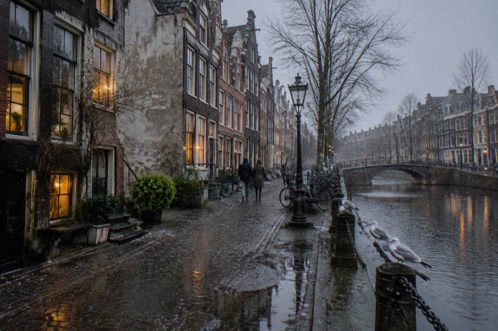 Row of narrow gabled buildings along an Amsterdam canal seen from street level