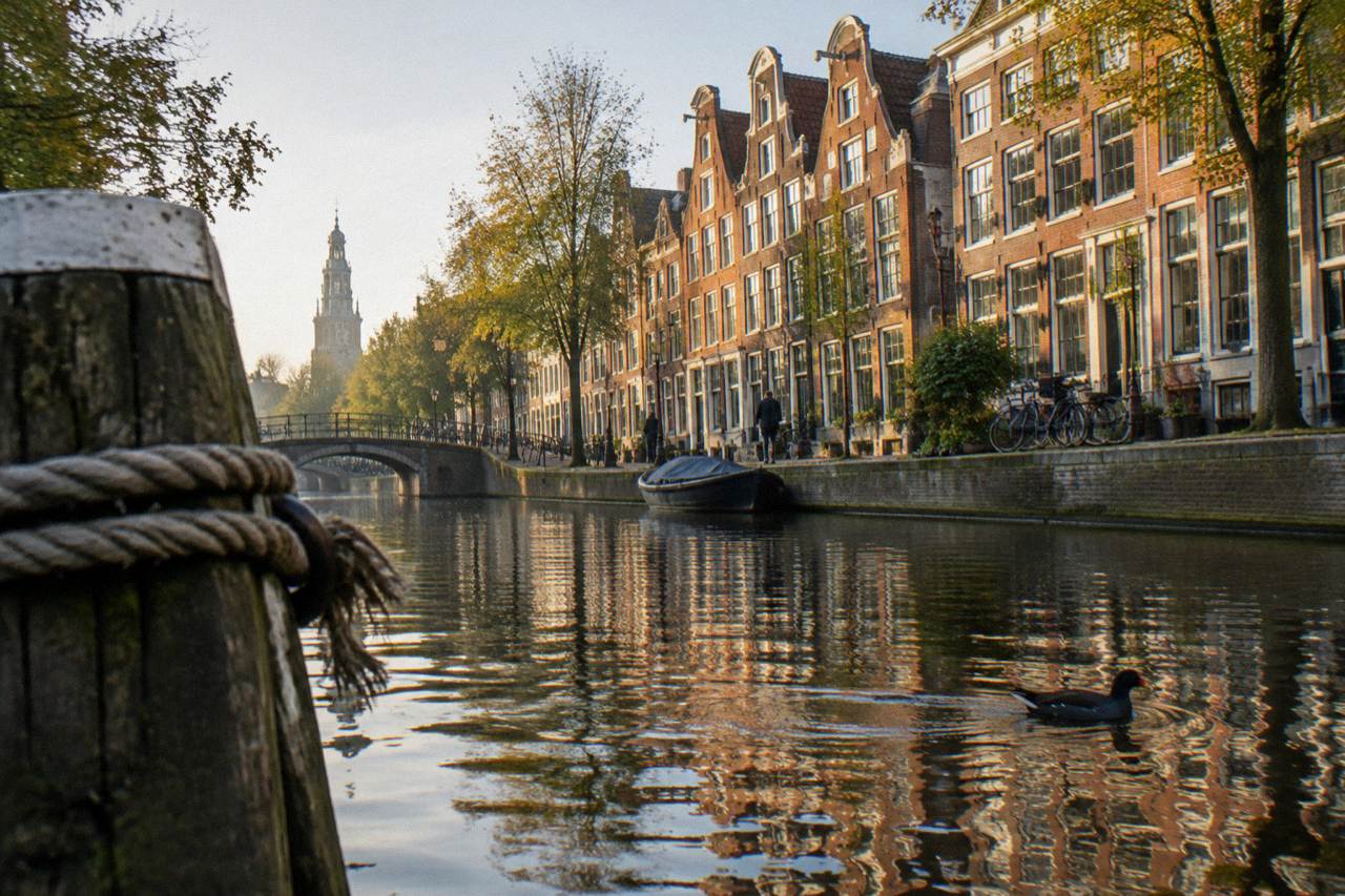 A narrow canal street in central Amsterdam with gabled houses and bicycles chained to a railing