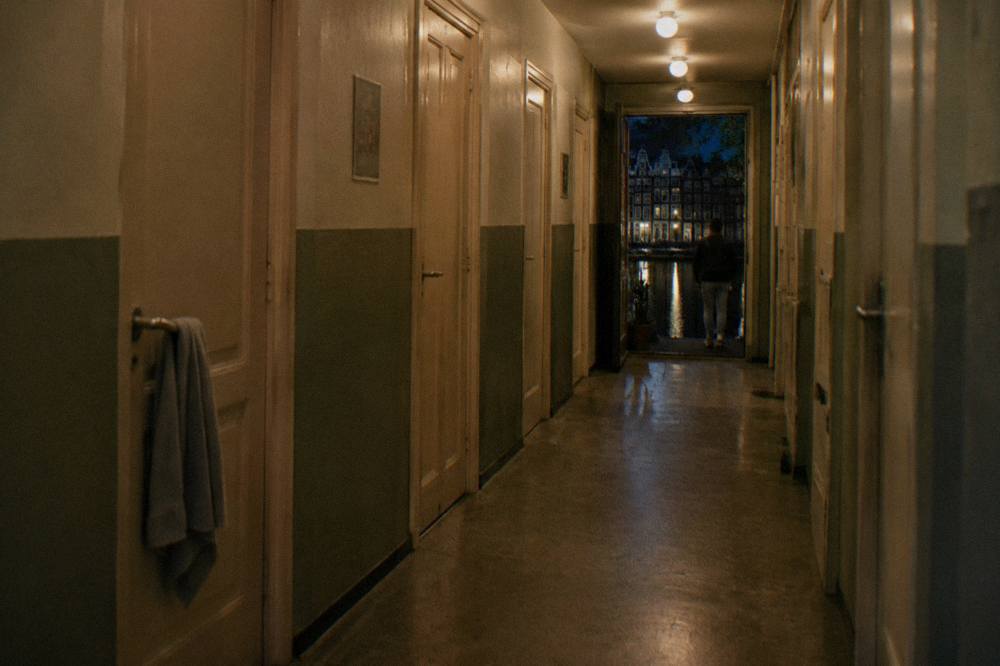 A hostel dormitory corridor with numbered doors and warm overhead lighting