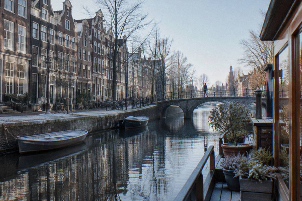 A canal in Amsterdam lined with narrow gabled houses and moored boats