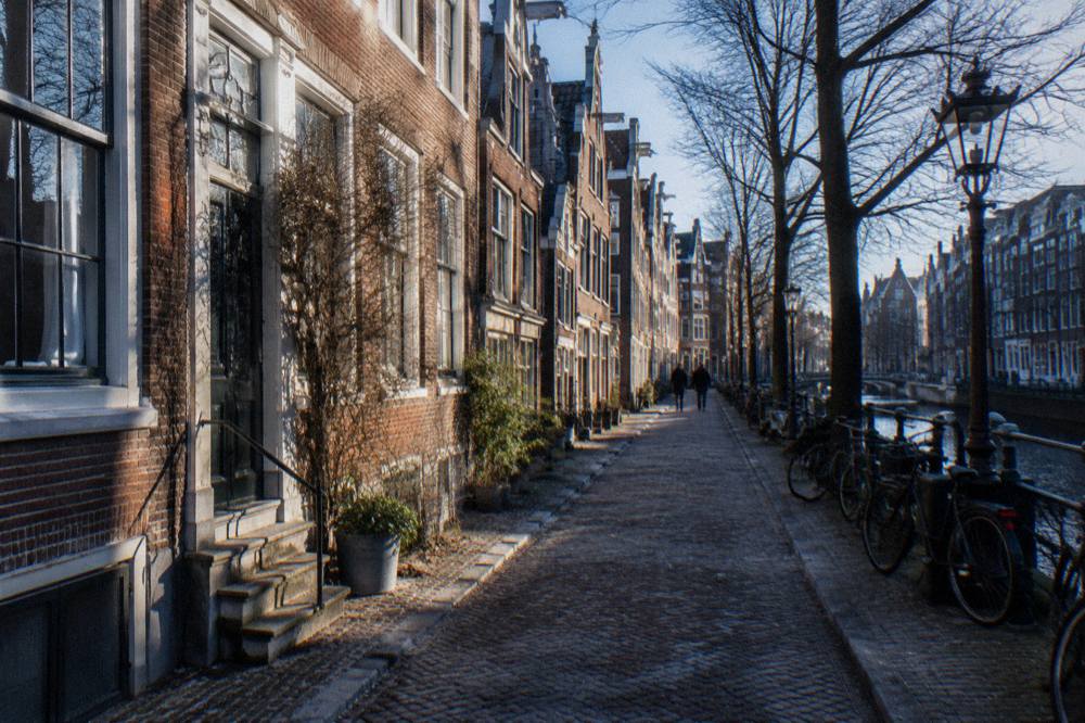 A narrow Amsterdam street with bicycles parked against canal house facades