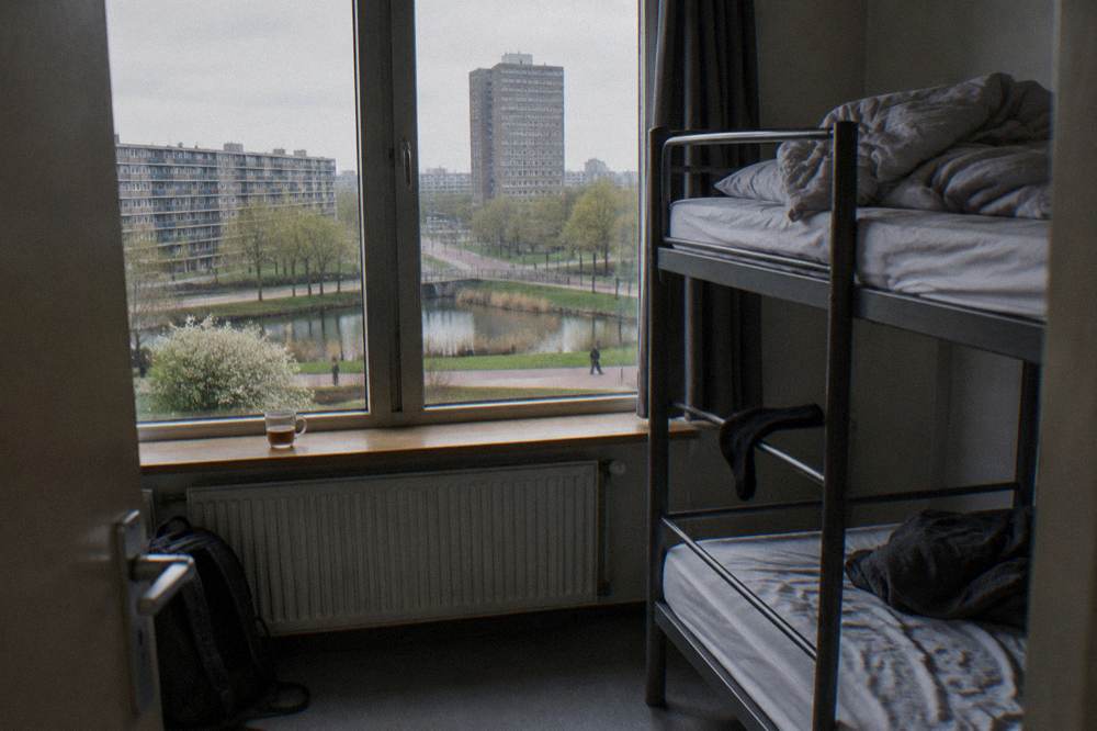 A simple hostel dorm room with bunk beds and a window