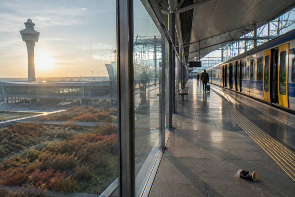 Train platform at an airport railway station with a modern terminal behind glass
