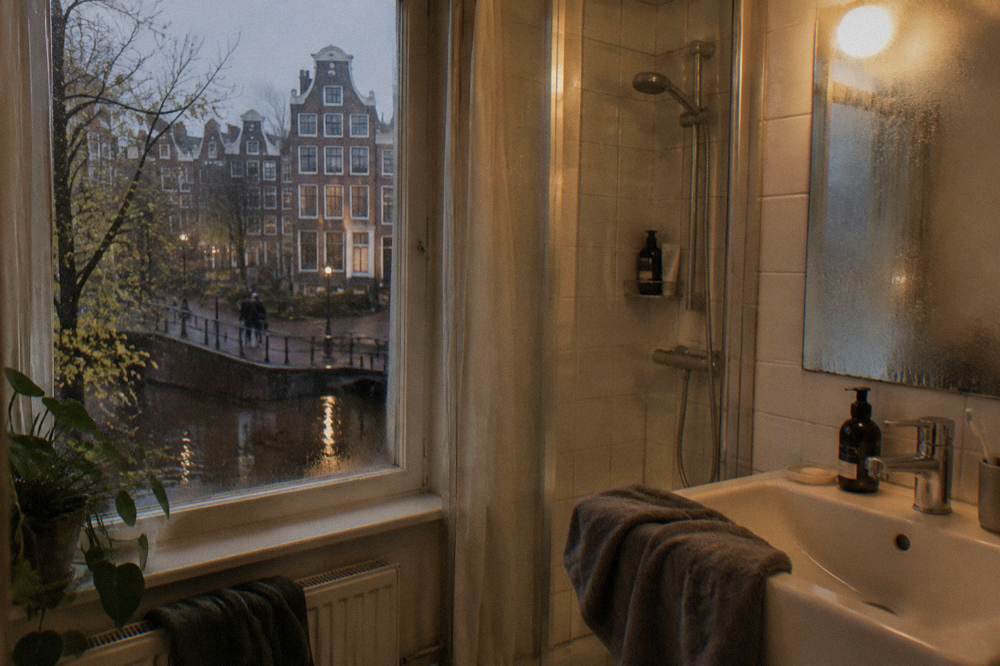 Compact en-suite hotel bathroom with shower, sink and mirror in warm light