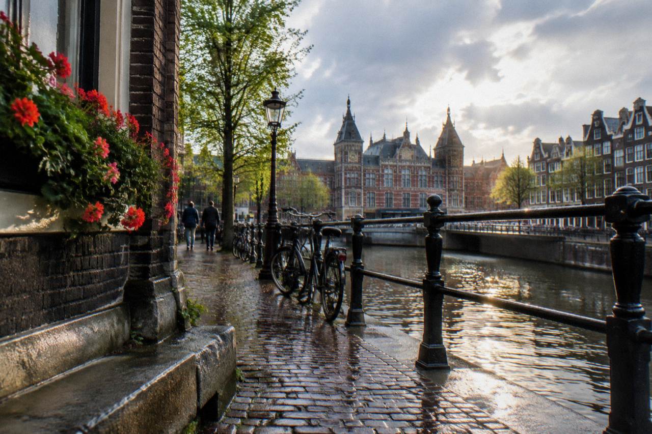 Narrow Amsterdam street with canal houses and bicycles parked against a railing