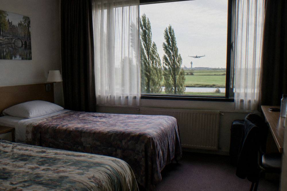 A simple twin hotel room with two single beds and a window facing trees