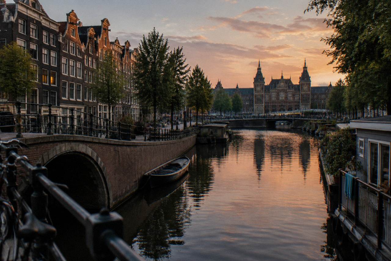 Canal houses and a bridge over calm water in an Amsterdam neighbourhood at dusk