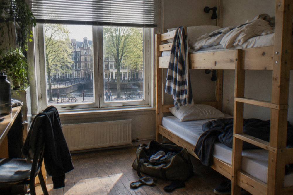 Bunk beds in a bright shared hostel dorm room with wooden frames