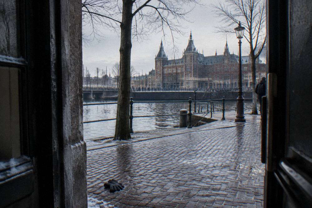 Empty Amsterdam canal street in winter with bare trees and parked bicycles