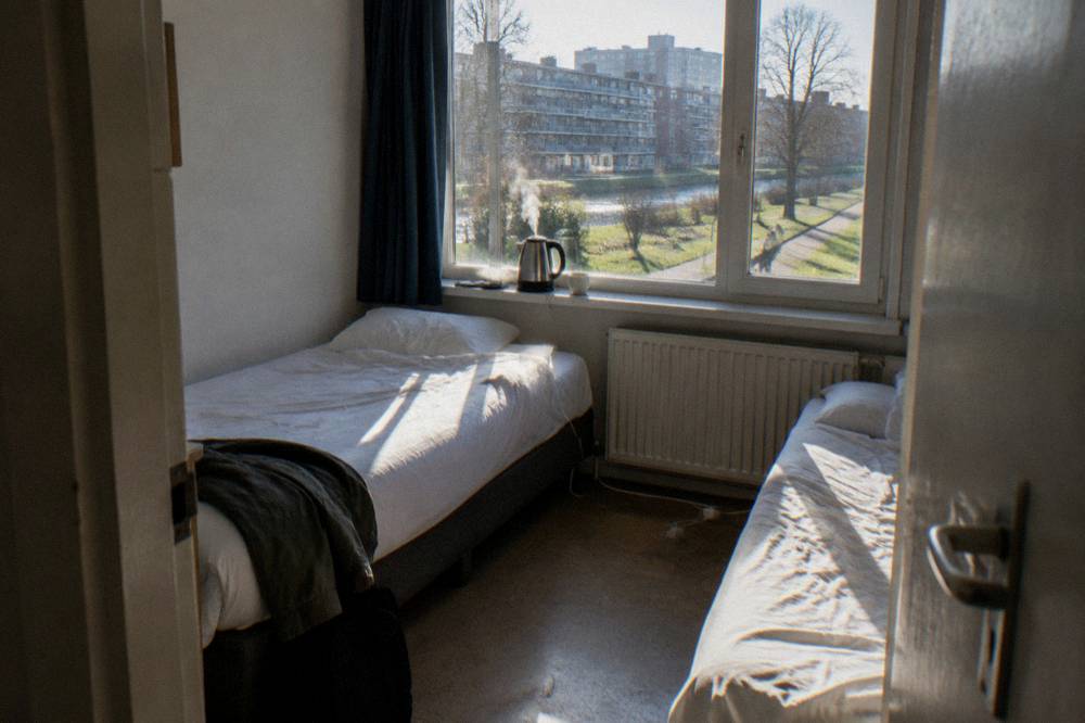 Budget hotel room with twin beds and simple furnishings by a window