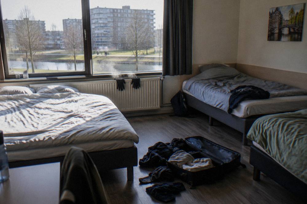 Spacious hotel family room with one double bed and two single beds beside a window