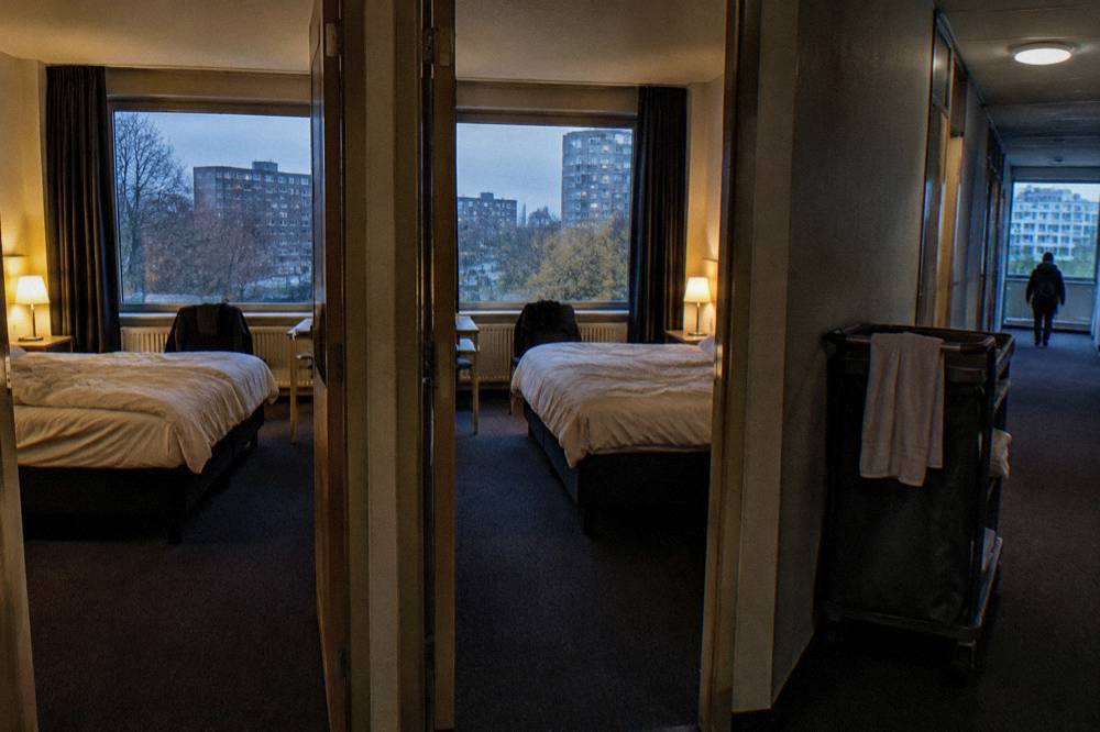 Two twin hotel rooms with neutral bedding seen from a corridor doorway
