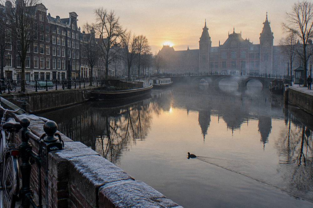 Amsterdam canal houses reflected in still water on a quiet winter morning