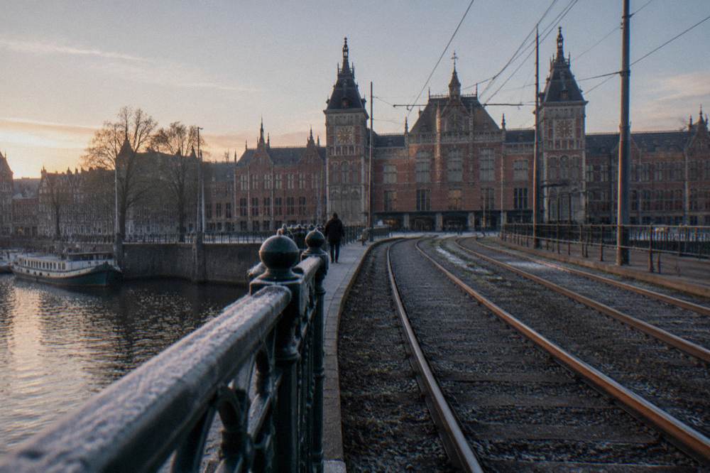 Tram tracks and station facade seen from a canal bridge in early morning light