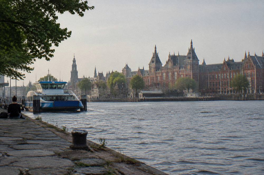 View across the water toward the station district skyline with rooftops and a stationary ferry