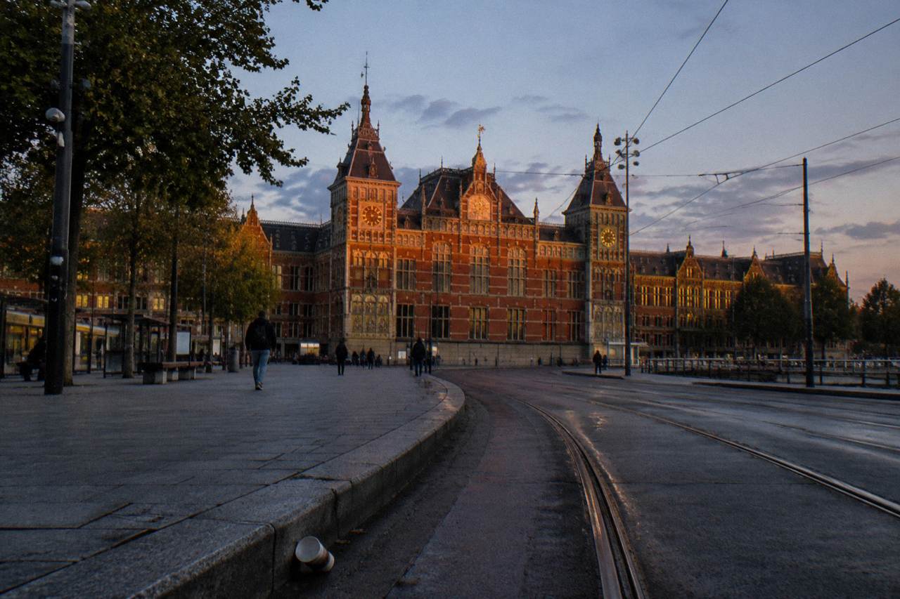 Amsterdam Centraal station facade and station square at dusk with bicycle parking and tram tracks