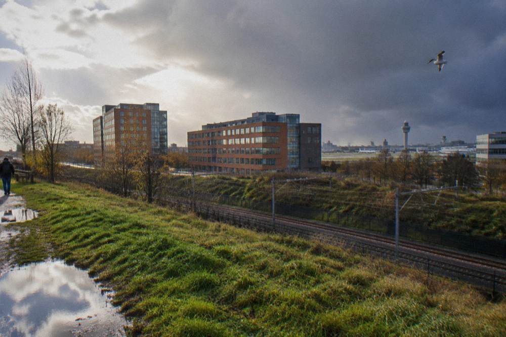 Modern hotel buildings near a rail line and airport skyline at the edge of a Dutch town